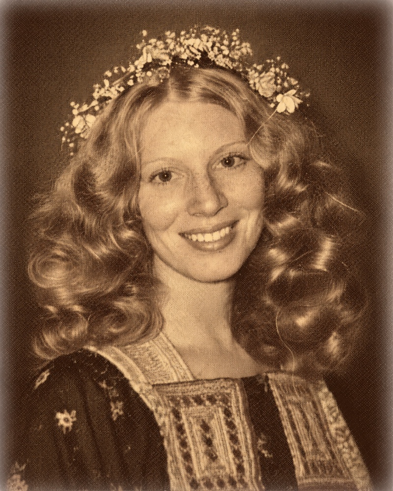 A young Judi smiling in a vintage portrait with curled hair and a floral crown